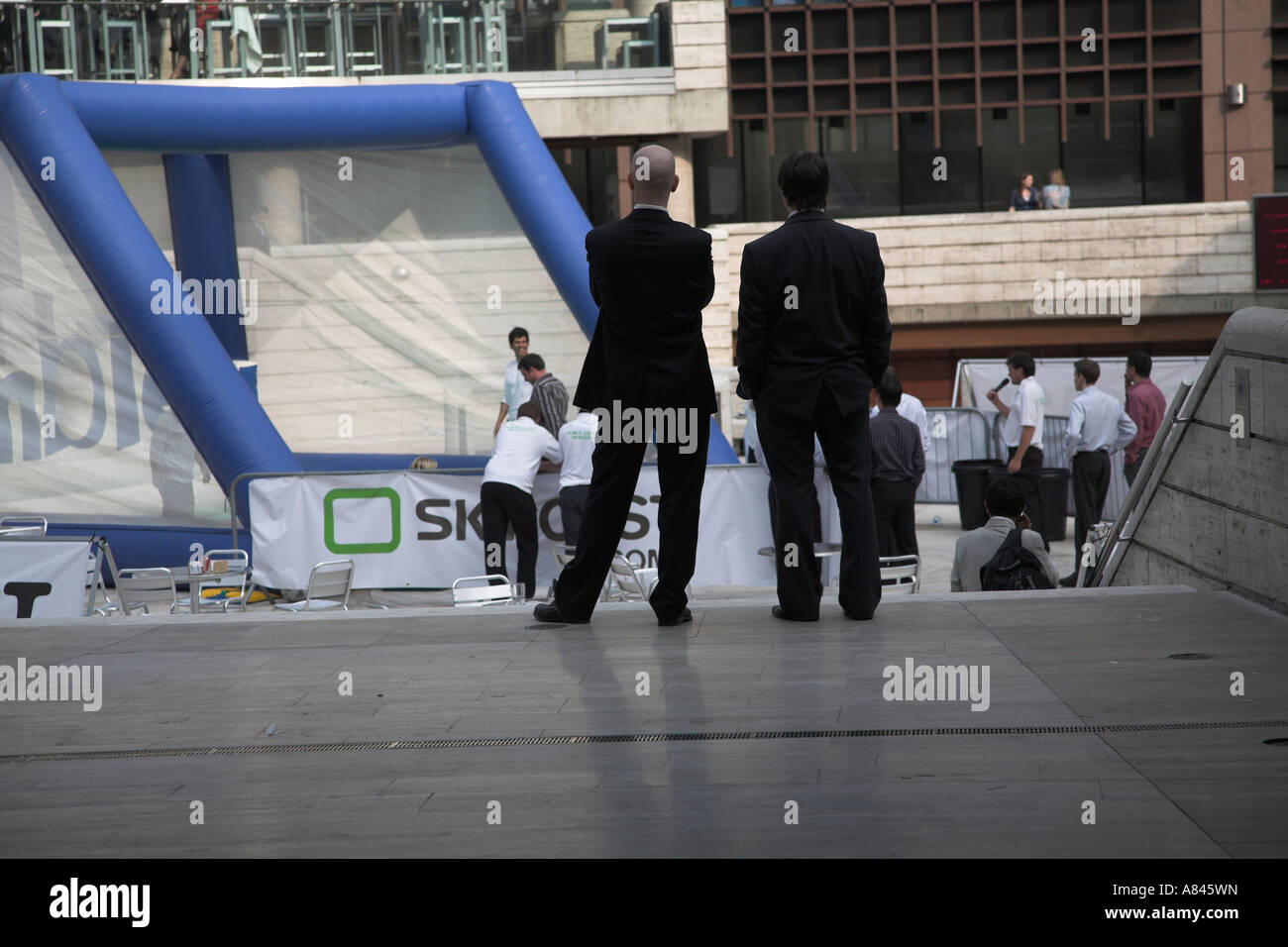 Two men in suits watching football entertainment show Broadgate Circus, City of London, England Stock Photo