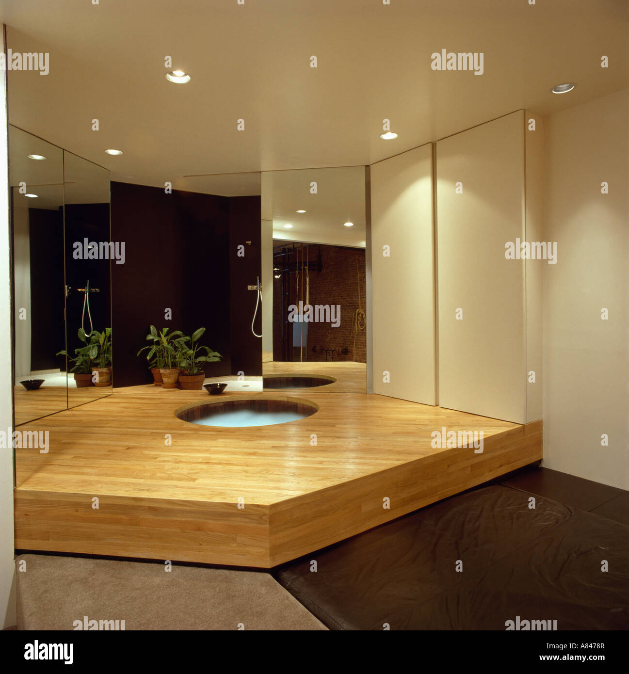 Hot tub in raised wooden platform in modern city bathroom with mirrored wall Stock Photo