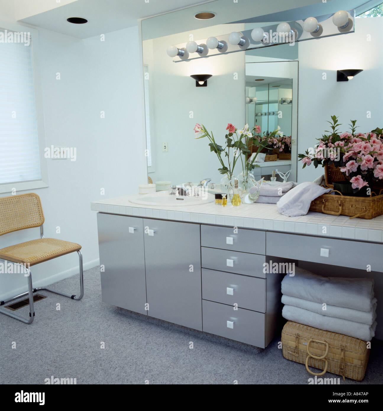 Gray storage unit below large mirror with lighting in modern bathroom