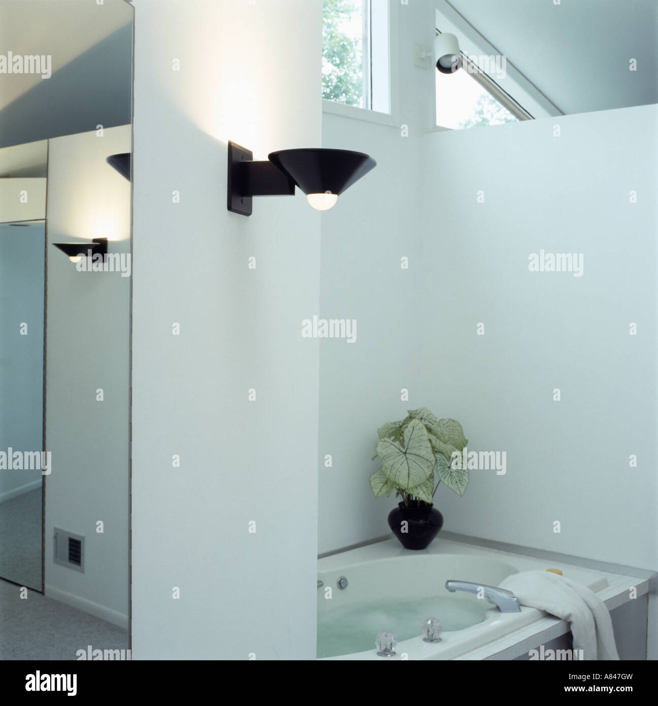 Modern white loft conversion bathroom with uplighter beside bath Stock Photo