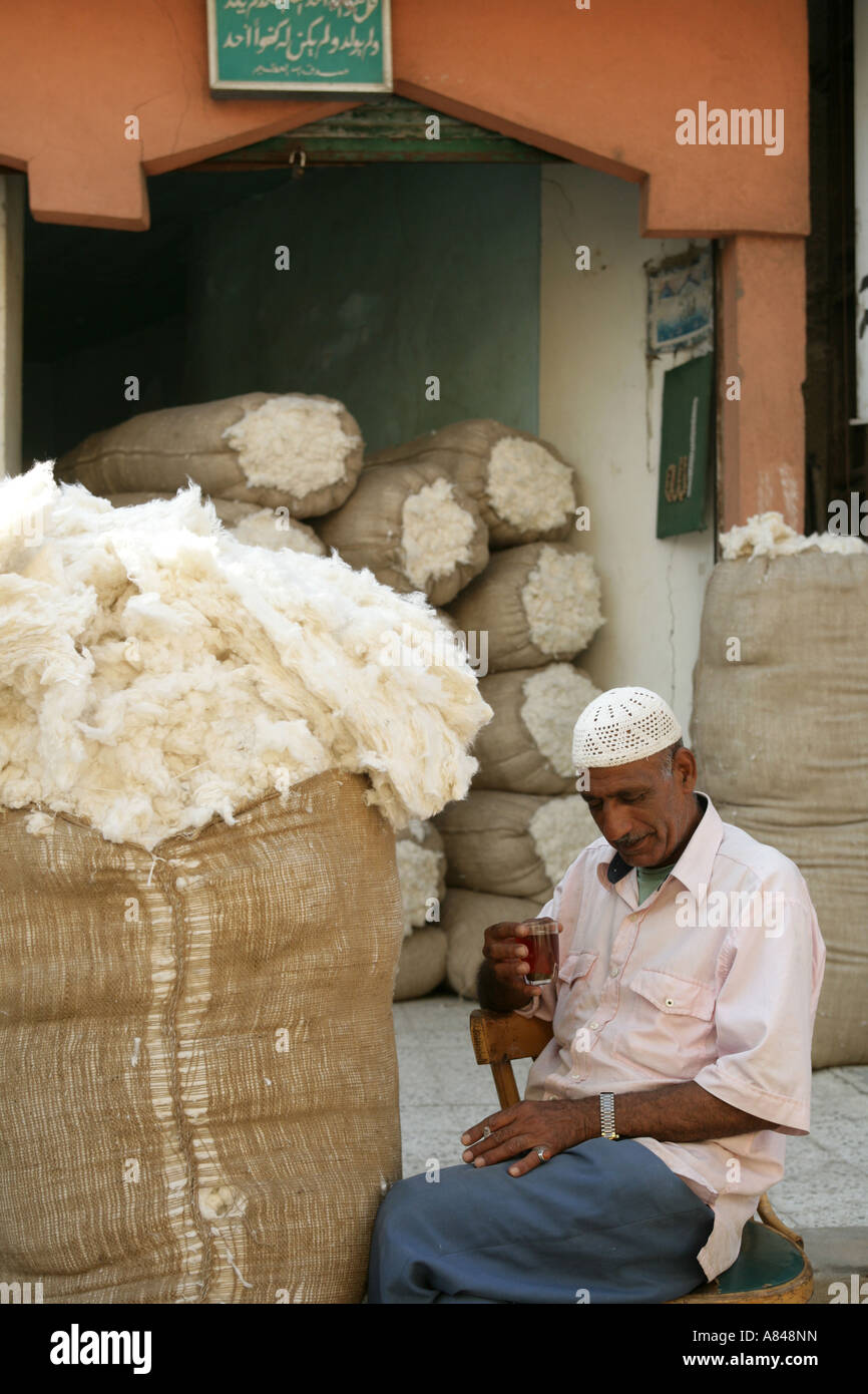 Cotton trader taking a break outside warehouse with overflowing sacks of cotton, Cairo, Egypt, Middle East Stock Photo