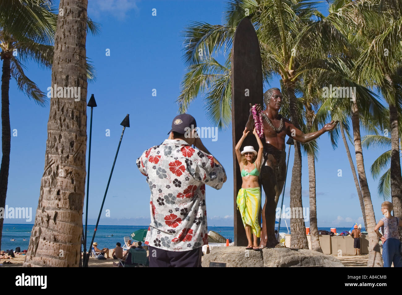 Tourist couple taking photos at Duke Kahanamoku statue at Kuhio Beach Park Waikiki Beach Honolulu Oahu Hawaii Stock Photo