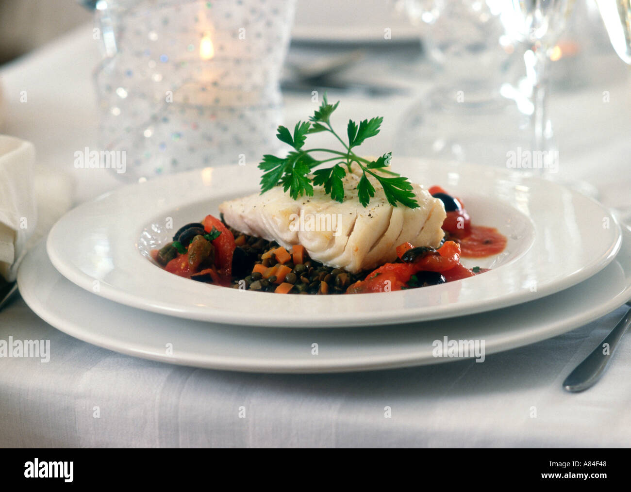 Elegant dish of cod on lentils in dinner party setting Stock Photo - Alamy