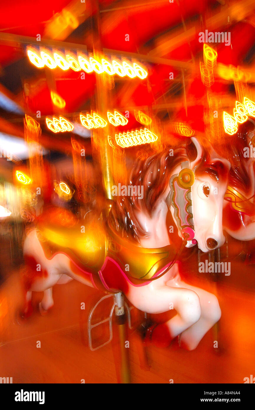 A carousel horse spins in a swirl of lights at a carnival fun zone Stock Photo