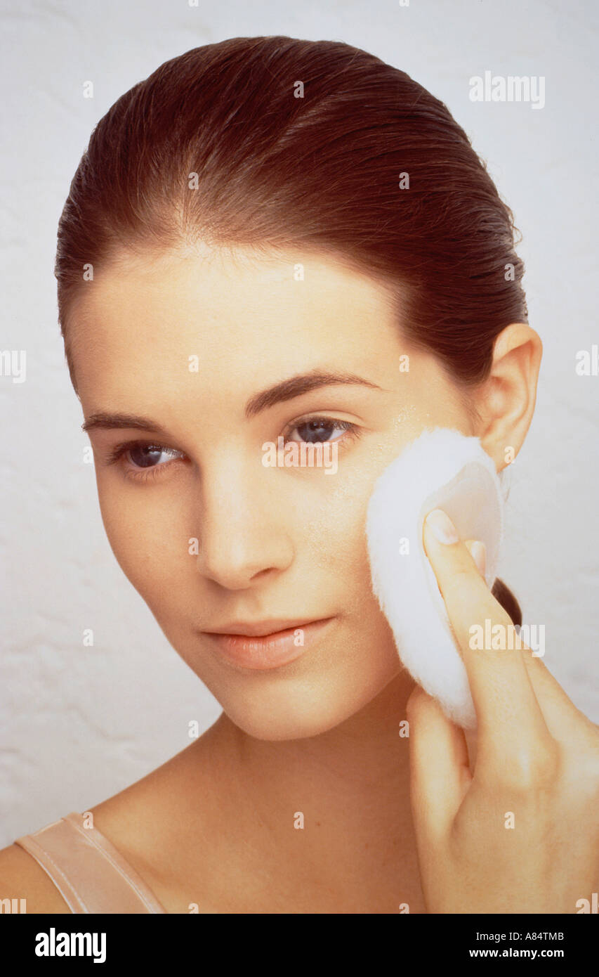 Indoor studio closeup portrait of young woman applying make-up. Stock Photo