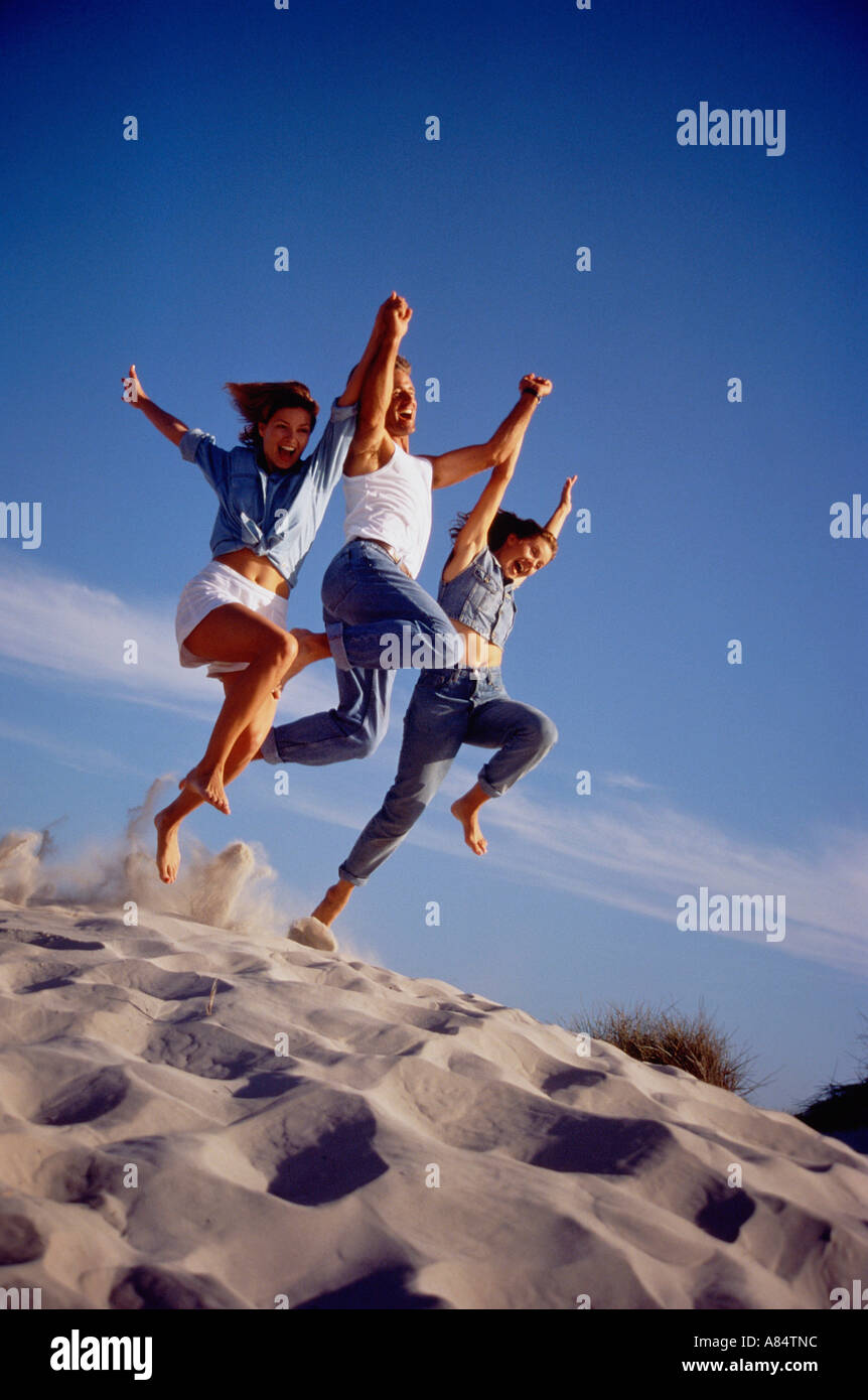 Three young people at the beach jumping off sand dune Stock Photo Alamy