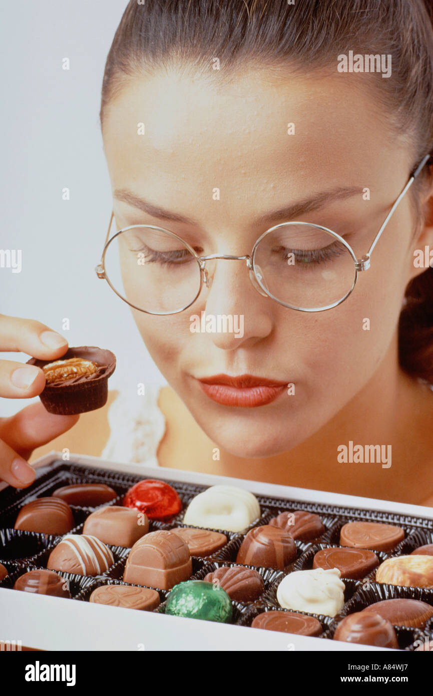 Studio portrait of woman about to eat a chocolate from a selection box. Stock Photo