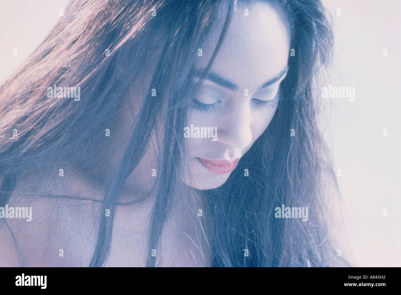 Closeup of beautiful dark haired woman looking down. Stock Photo