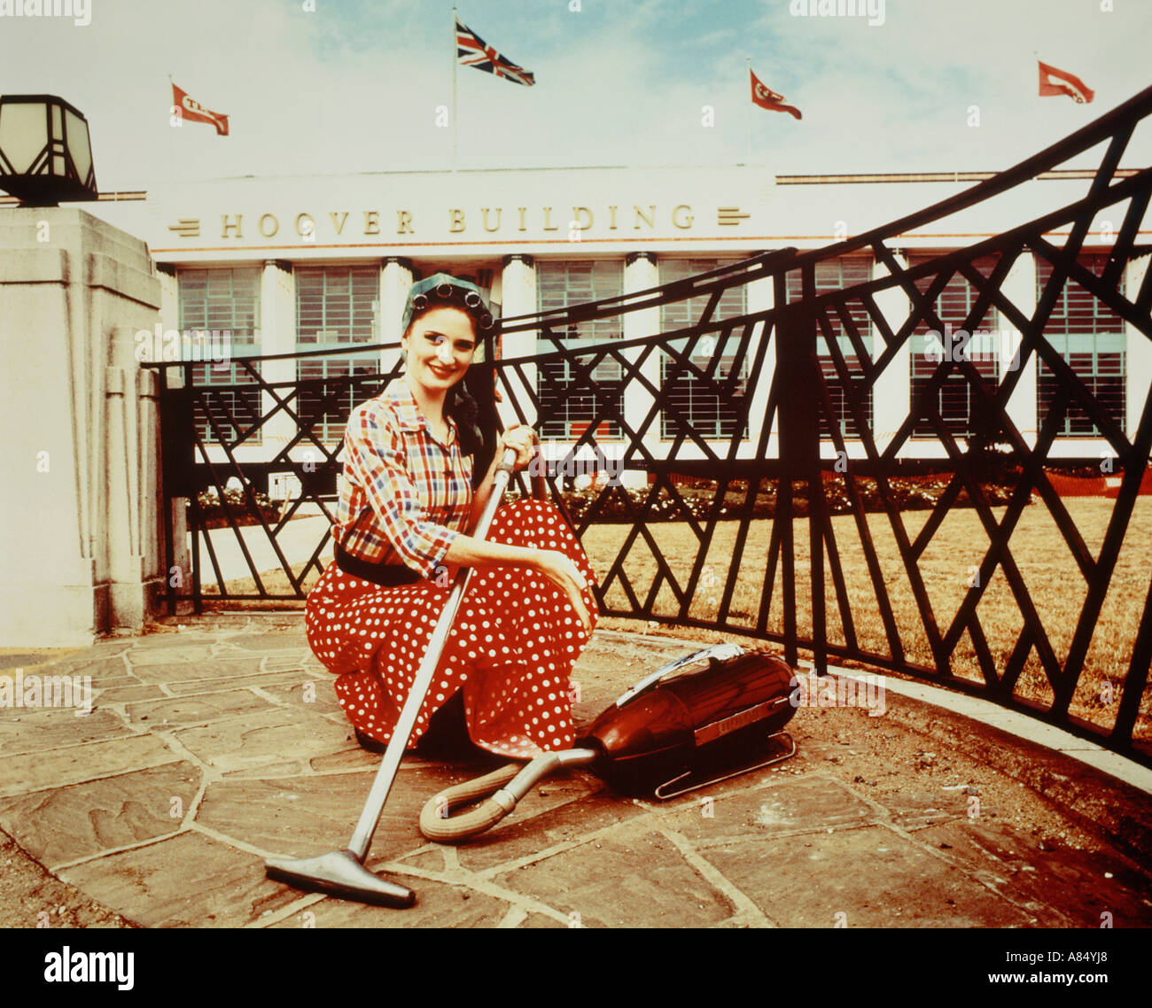 Period advertising concept of 1950s style woman with vacuum cleaner outside the Hoover Building, London, UK. Stock Photo