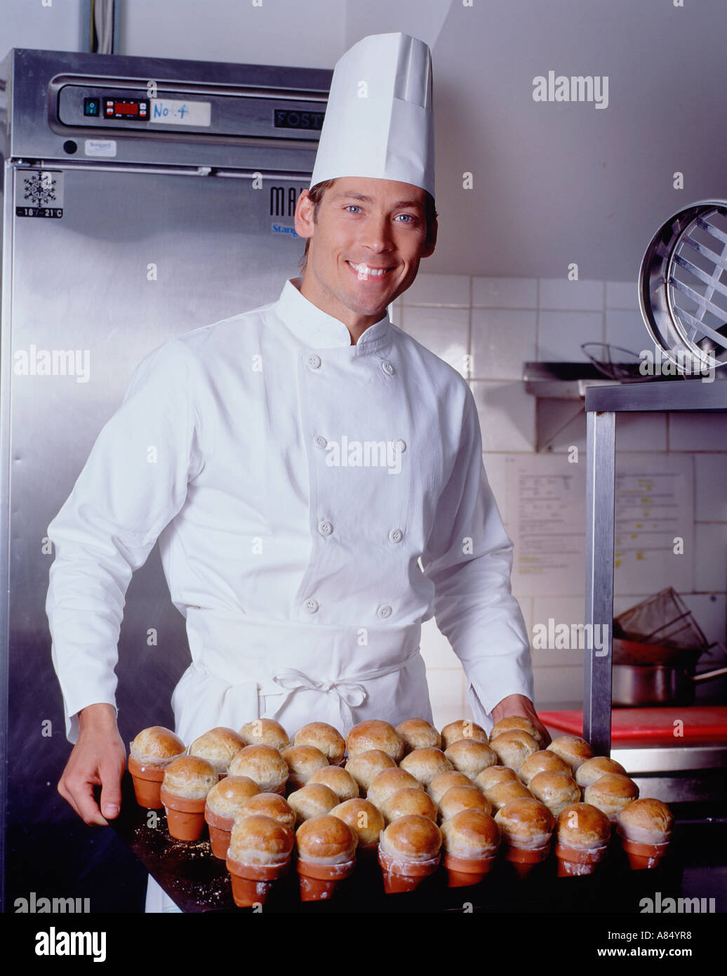 Chef in hotel kitchen holding tray of freshly baked brioche buns. Stock Photo