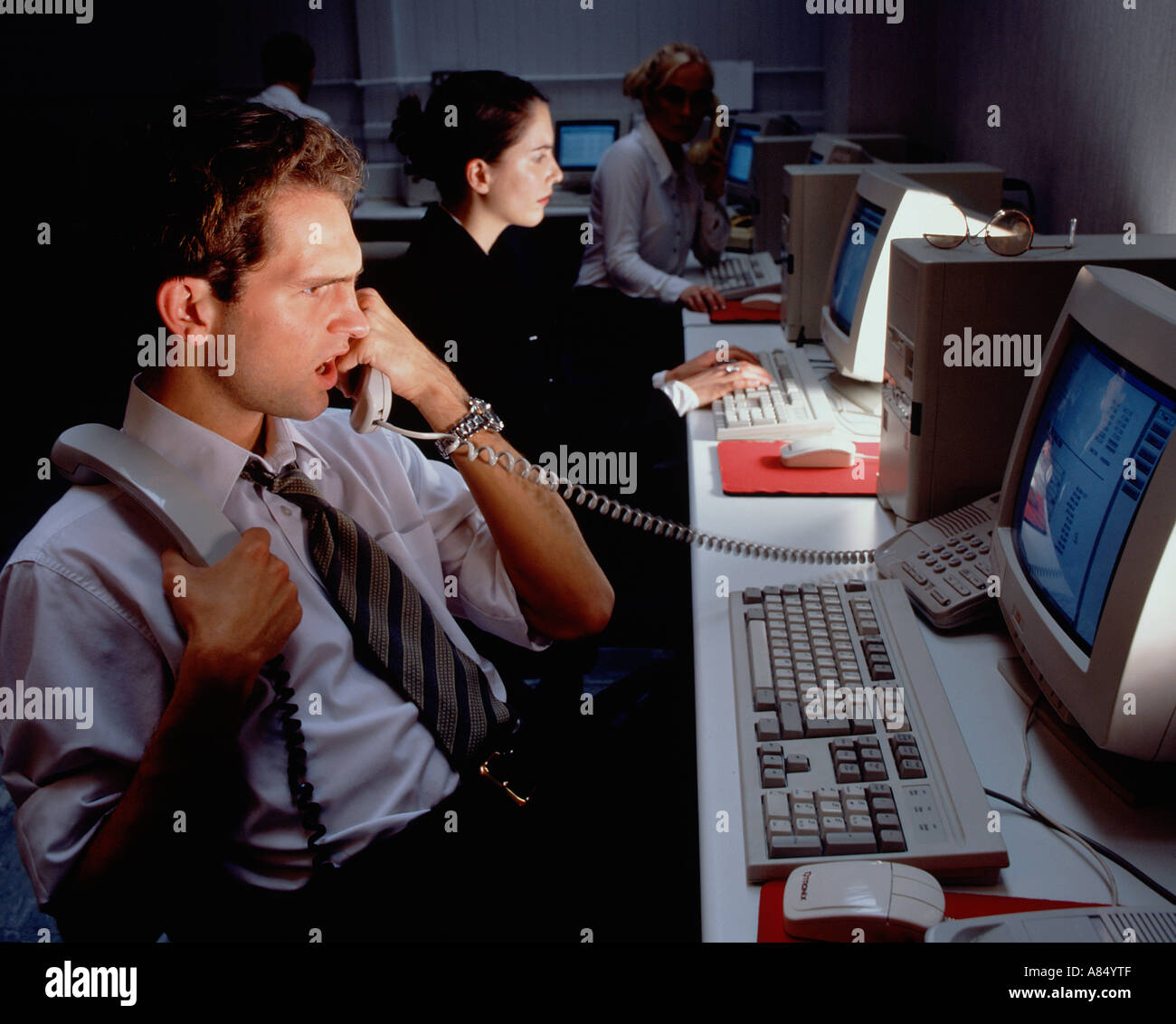 Call centre telephone operators with computer monitor screens at night ...