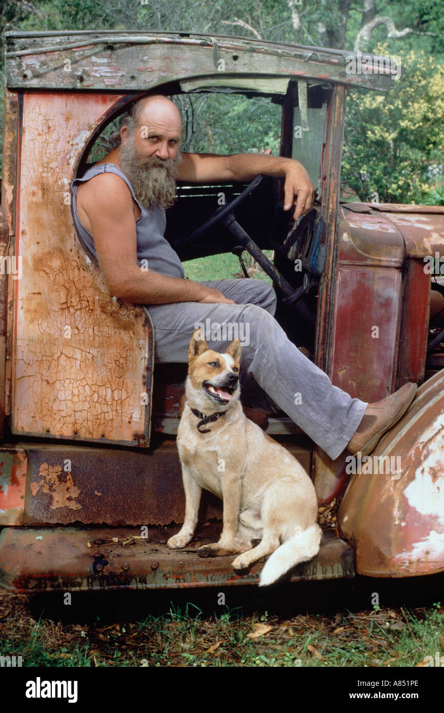 Australia. Man seated in dilapidated vintage truck cab with his dog. Stock Photo