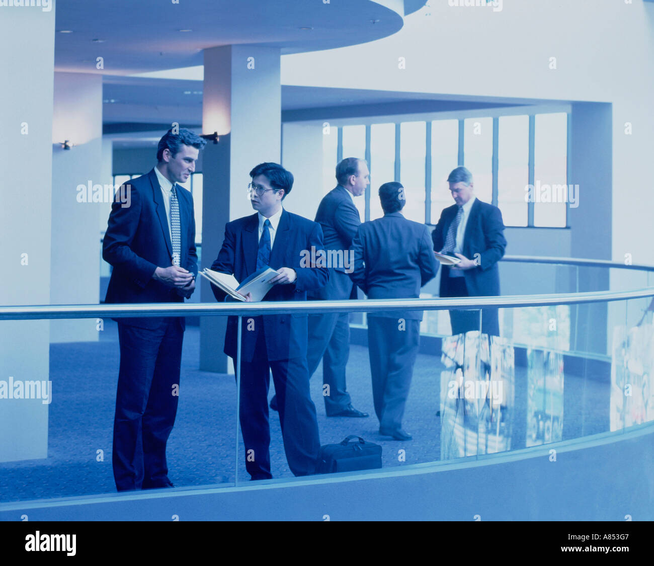 Group of businessmen standing on mezzanine floor, taking a break during conference. Stock Photo