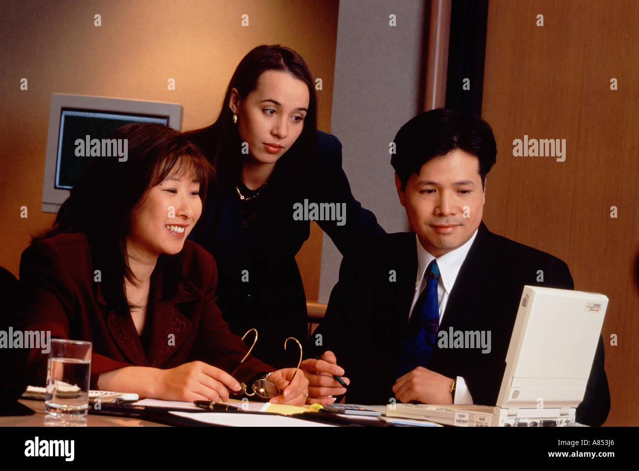 Three business people working in office with laptop computer. Stock Photo