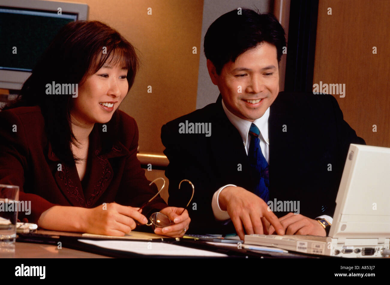 Indoor close-up of man and woman in office working with laptop computer. Stock Photo