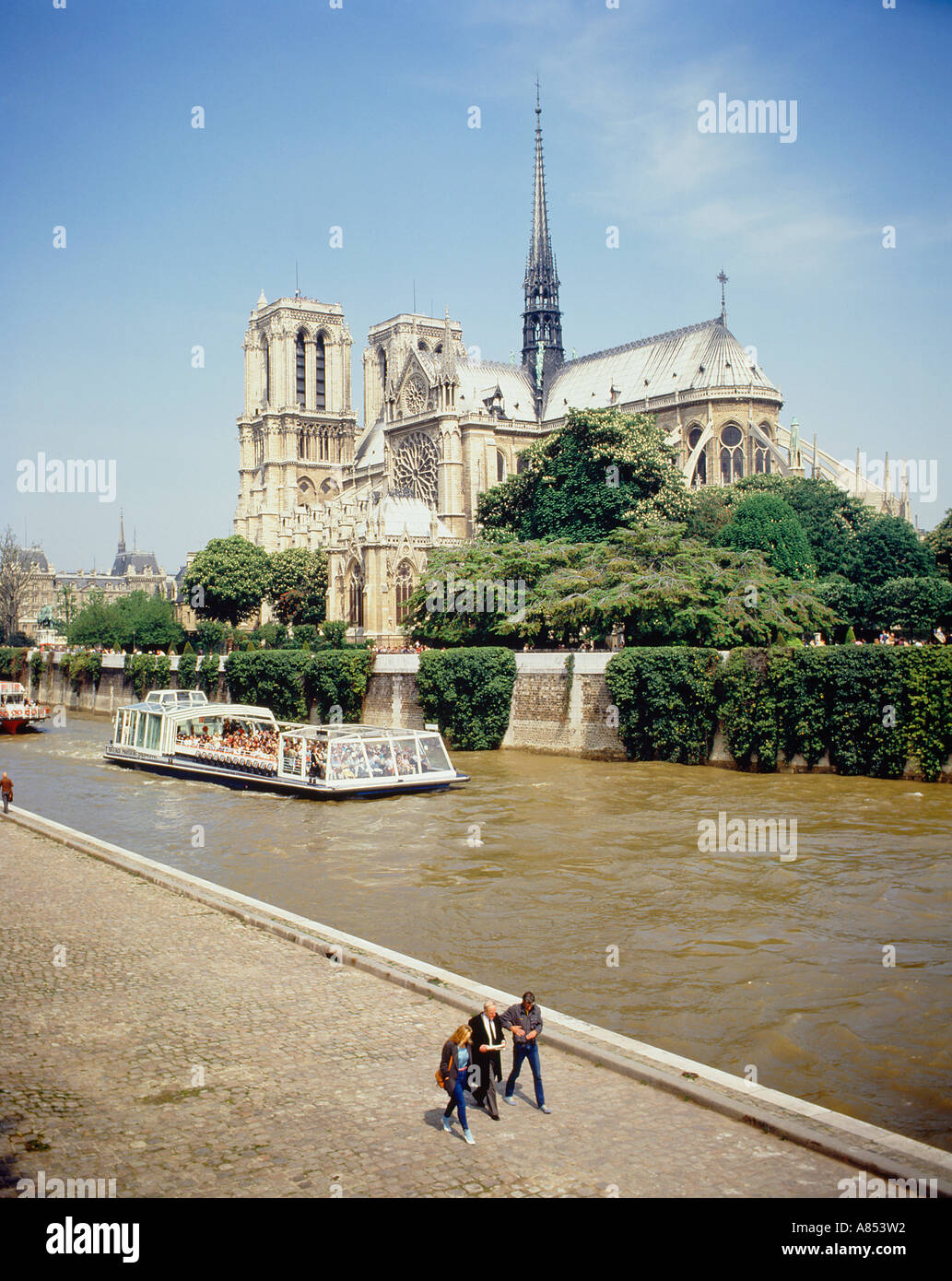 France. Paris. Notre Dame cathedral. People walking by the River Seine with tourist boat. Stock Photo
