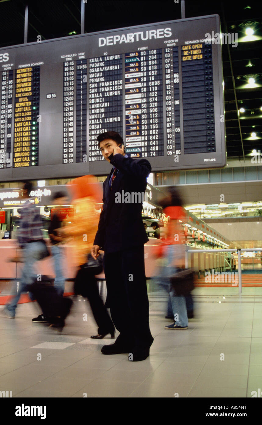 Young man wearing a business suit, using a mobile 'phone inside an airport terminal. Stock Photo