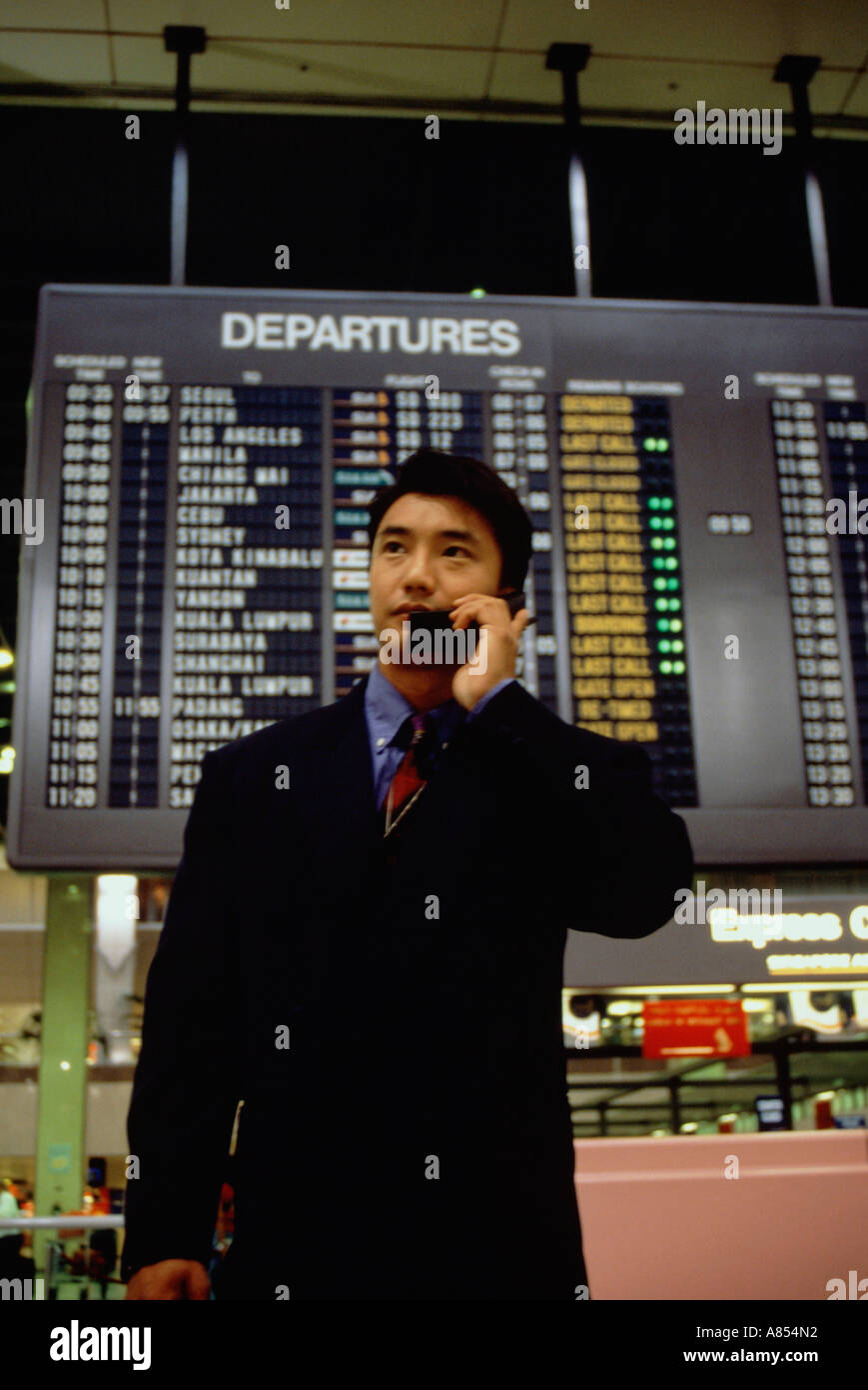 Young man wearing a business suit, using a mobile 'phone inside an airport terminal. Stock Photo