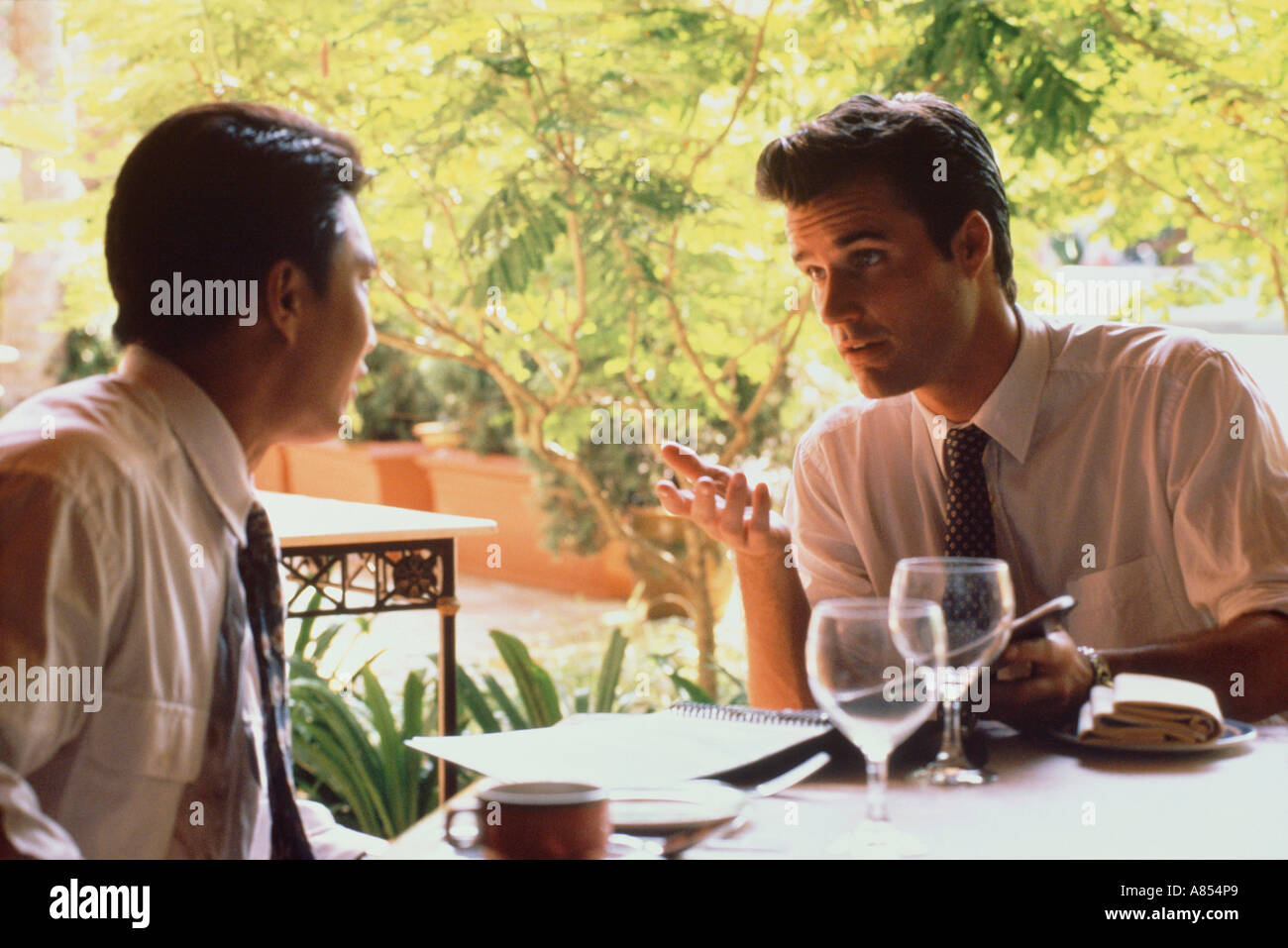 Two business men having lunch outdoors on restaurant terrace. Singapore. Stock Photo