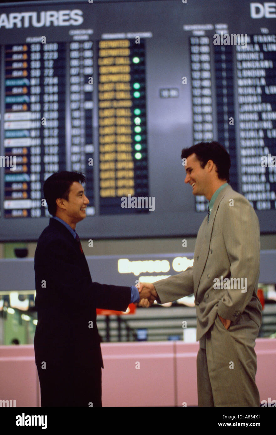 Two men handshake greeting in airport terminal building. Stock Photo