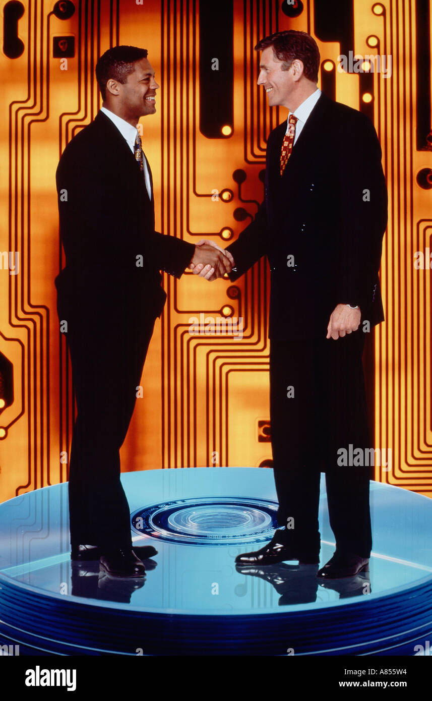 Concept. Two business men handshake montaged on computer disc media and circuit. Stock Photo