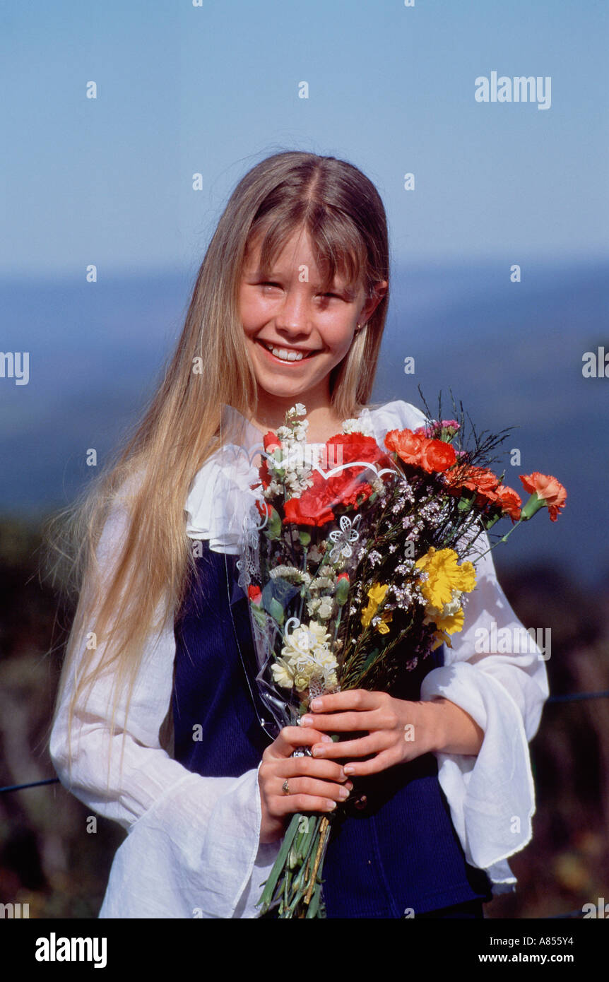 Outdoor portrait of young girl holding bunch of flowers. Stock Photo