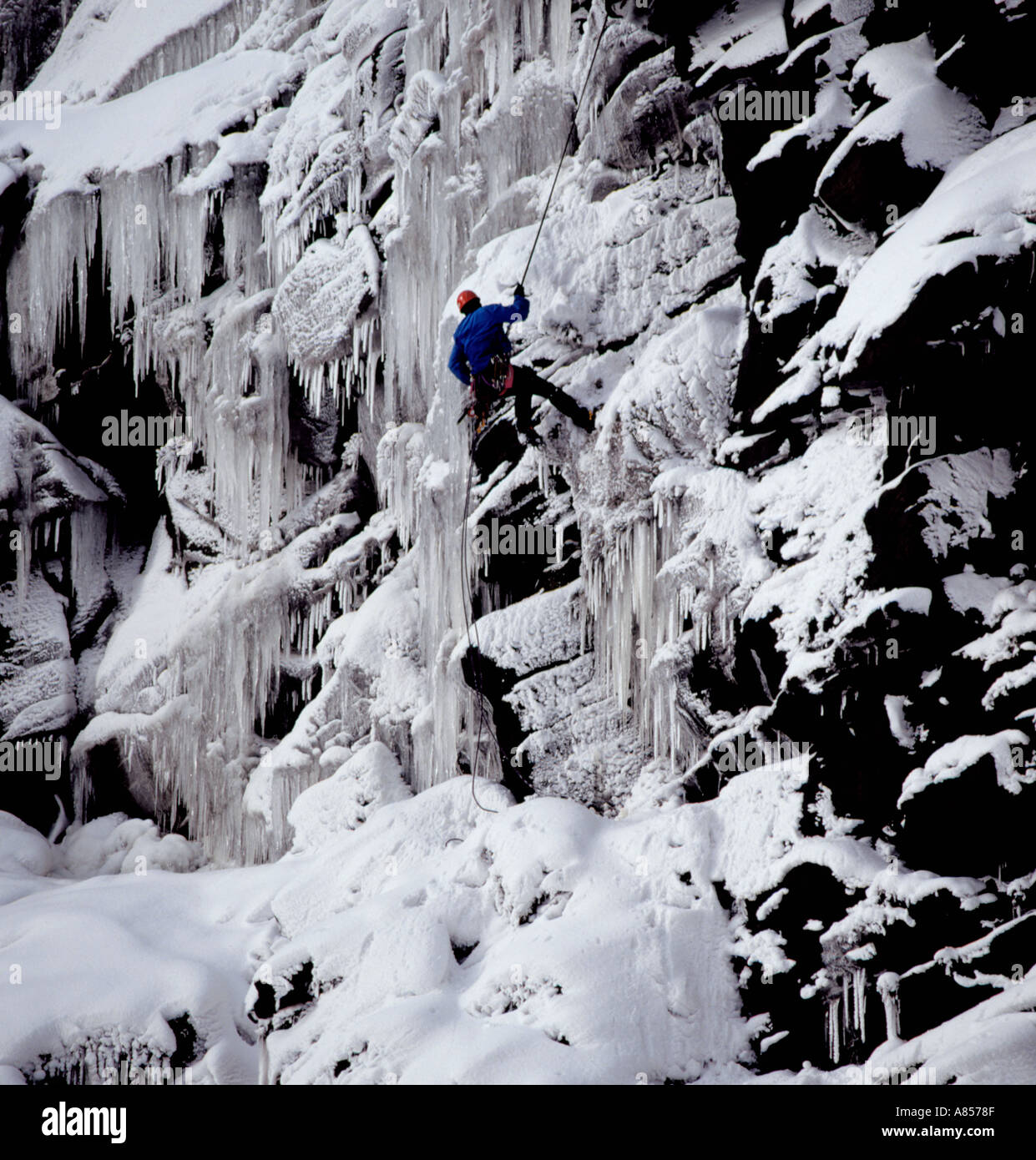 Climber abseilling down Kinder Downfall in winter, Kinder Scout, Peak District National Park, Derbyshire, England, UK. Stock Photo