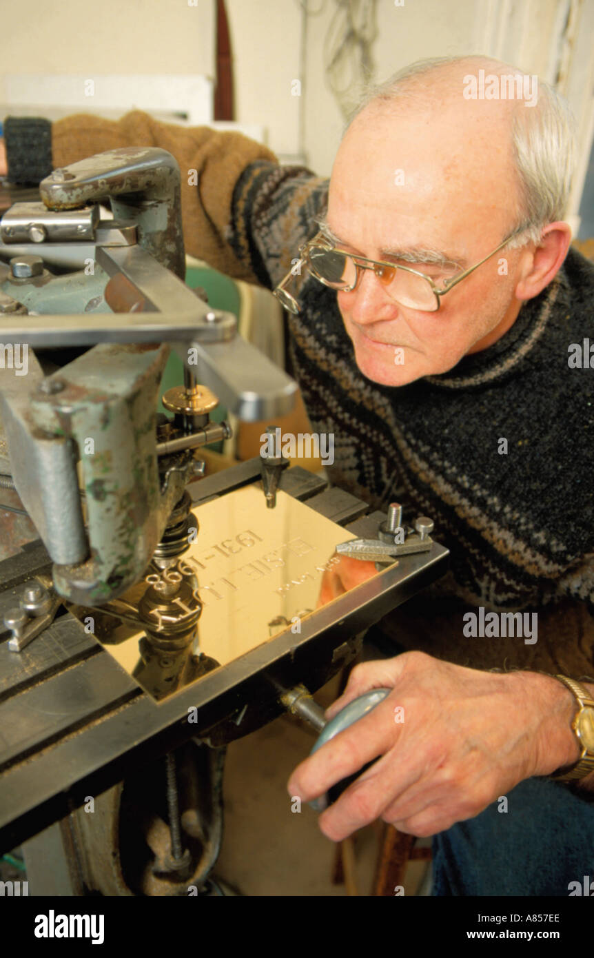 Engraver at work using a machine to engrave a brass plaque Stock Photo