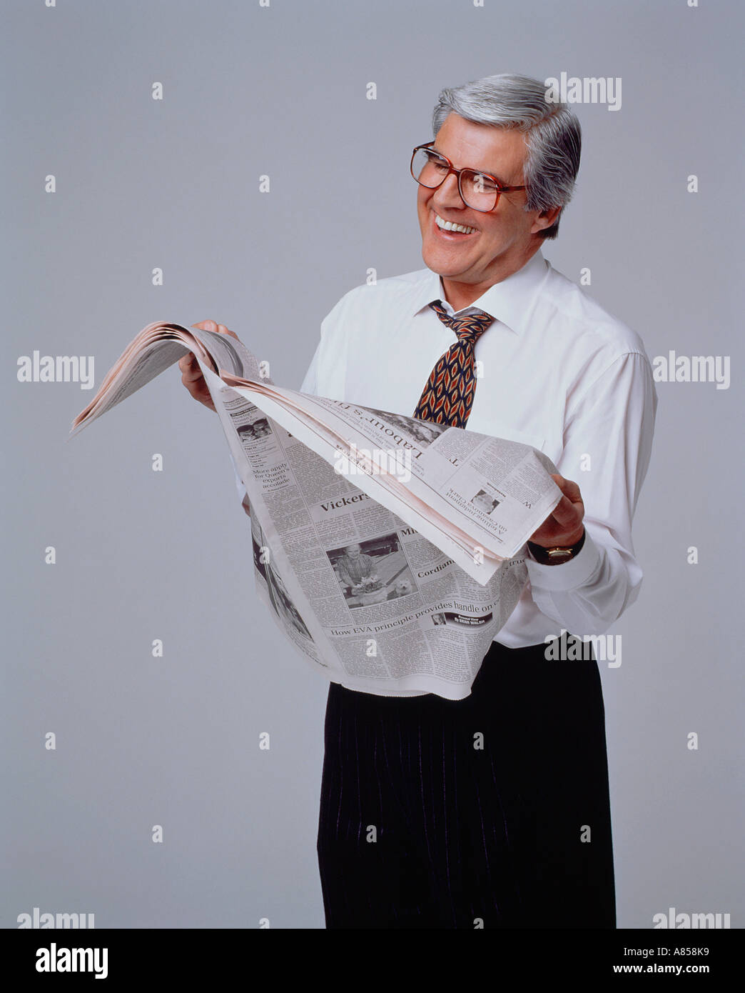 Middle aged man reading newspaper in studio. Stock Photo