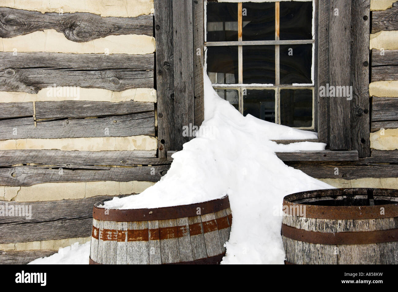 A cottage window with snow and old rain barrels inside Fort Gibralter