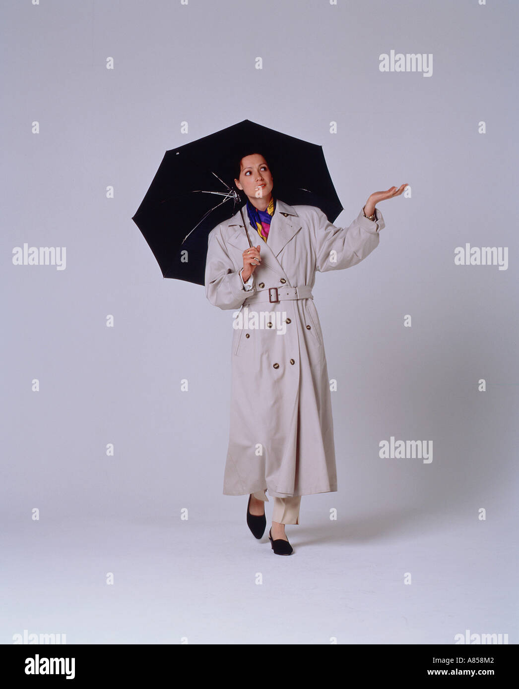 Studio image of young woman in raincoat with umbrella. Stock Photo