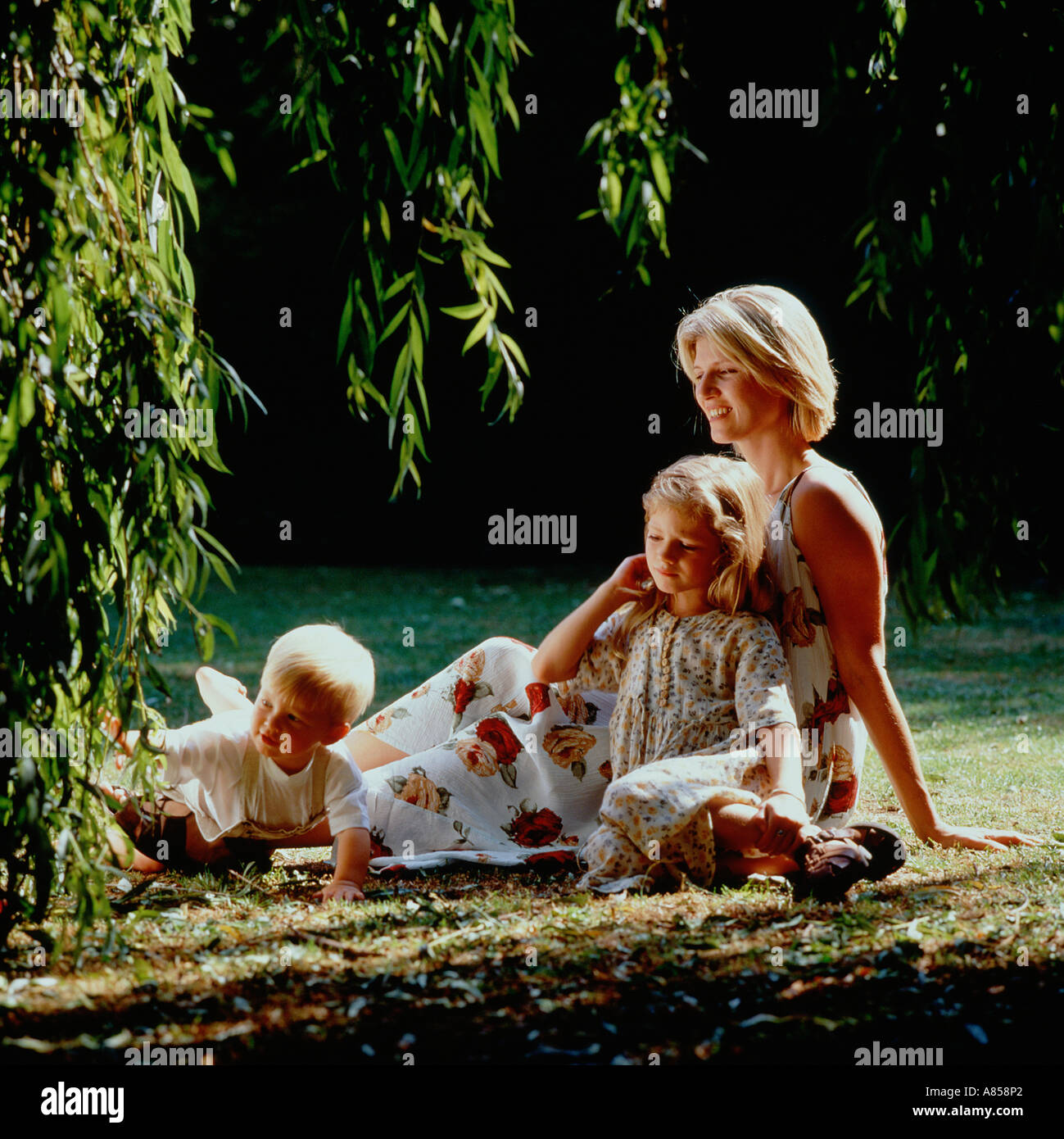 Outdoor portrait of single blond mother and two children, son and daughter in the park. Stock Photo