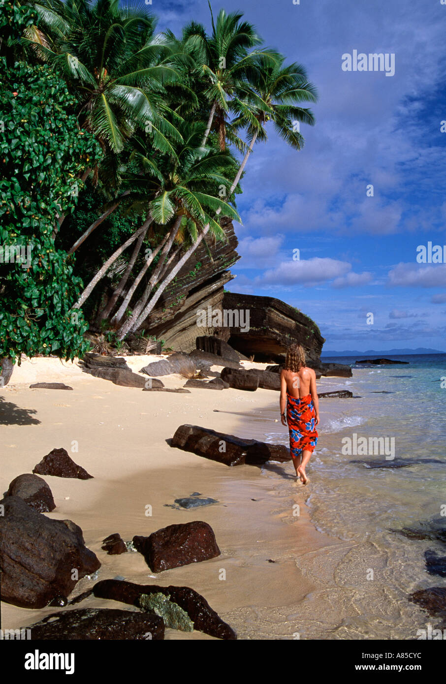 Fiji Raranitingga uninhabited island beach woman in red wrap walking at waters edge Stock Photo