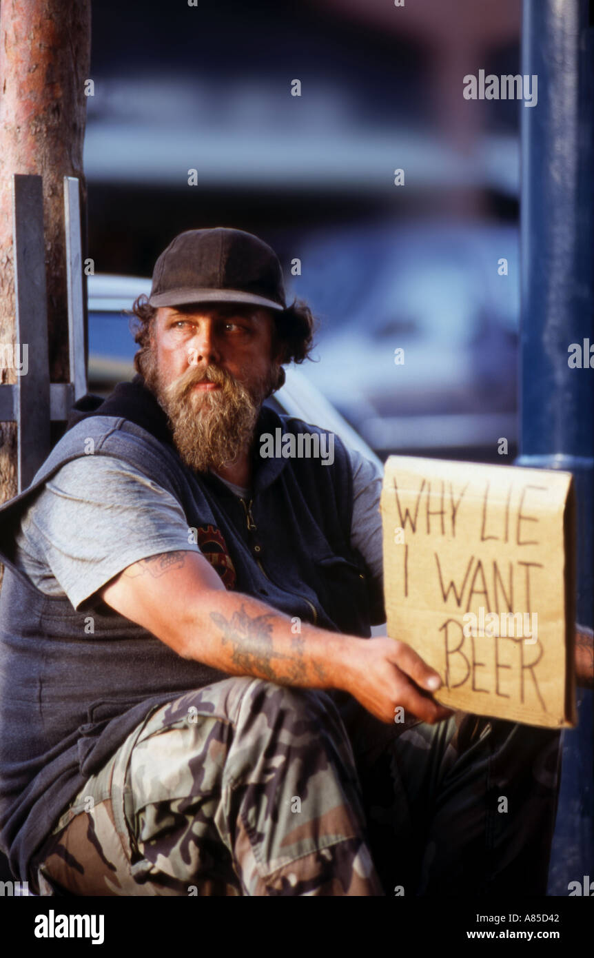 Homeless beggar begging for alcohol or beer on city street Stock Photo