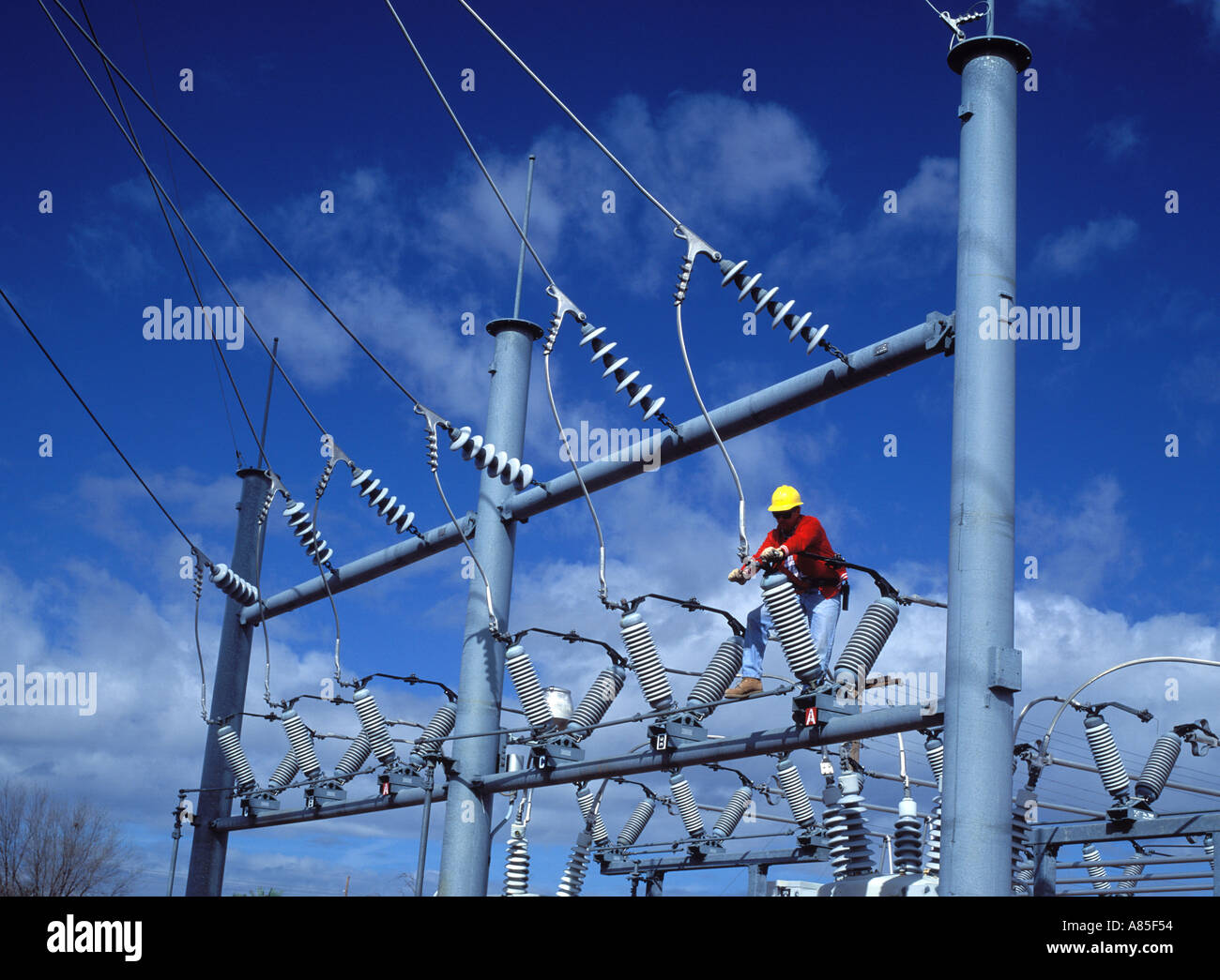 Electrical worker repairs power lines at an electrical substation Stock