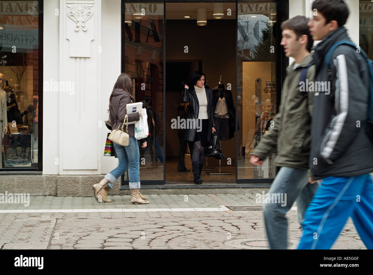 Woman Leaving A Clothes Shop On A Busy European High Street Stock Photo