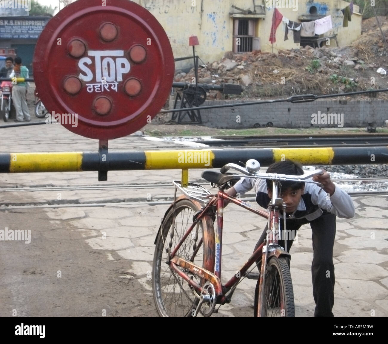 A boy pushing his bike underneath a barrier at a railway crossing in Patna, India Stock Photo - Alamy