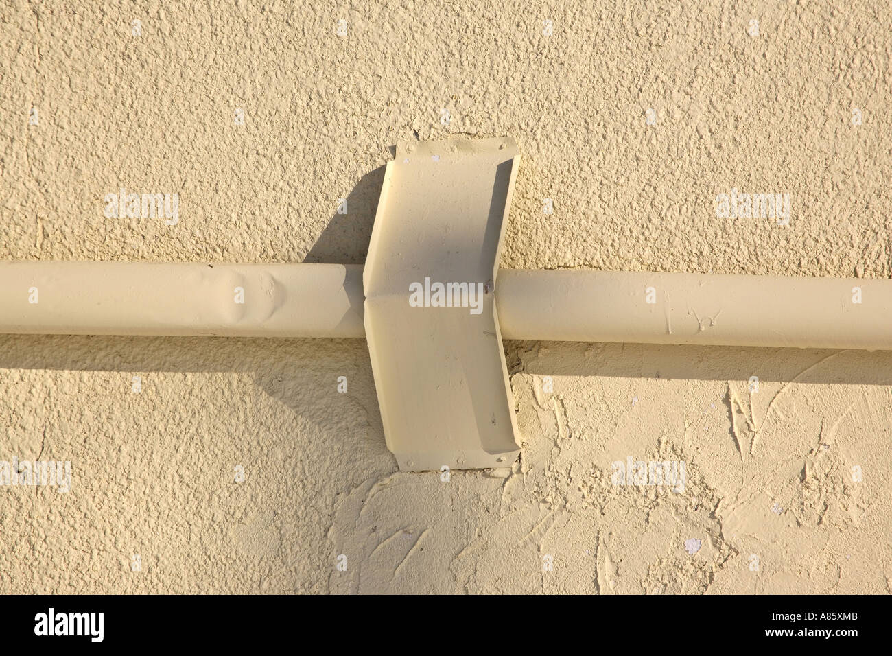 Bracket holding pipe on stucco wall Stock Photo Alamy