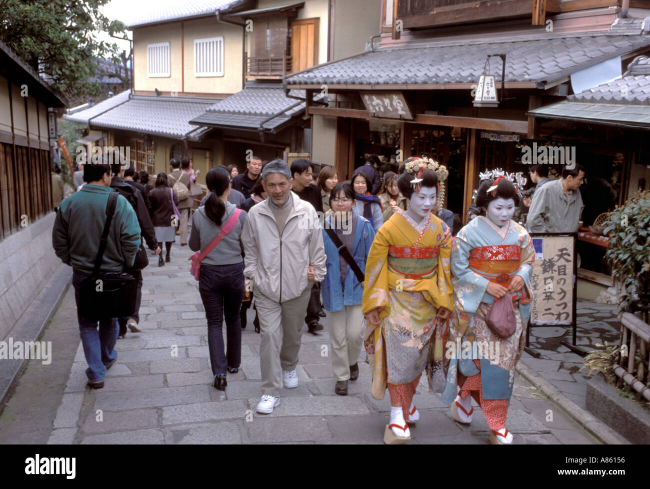 Two maiko, or geisha in training, walking along a narrow cobblestone backstreet in Kyoto's Higashiyama district. Stock Photo