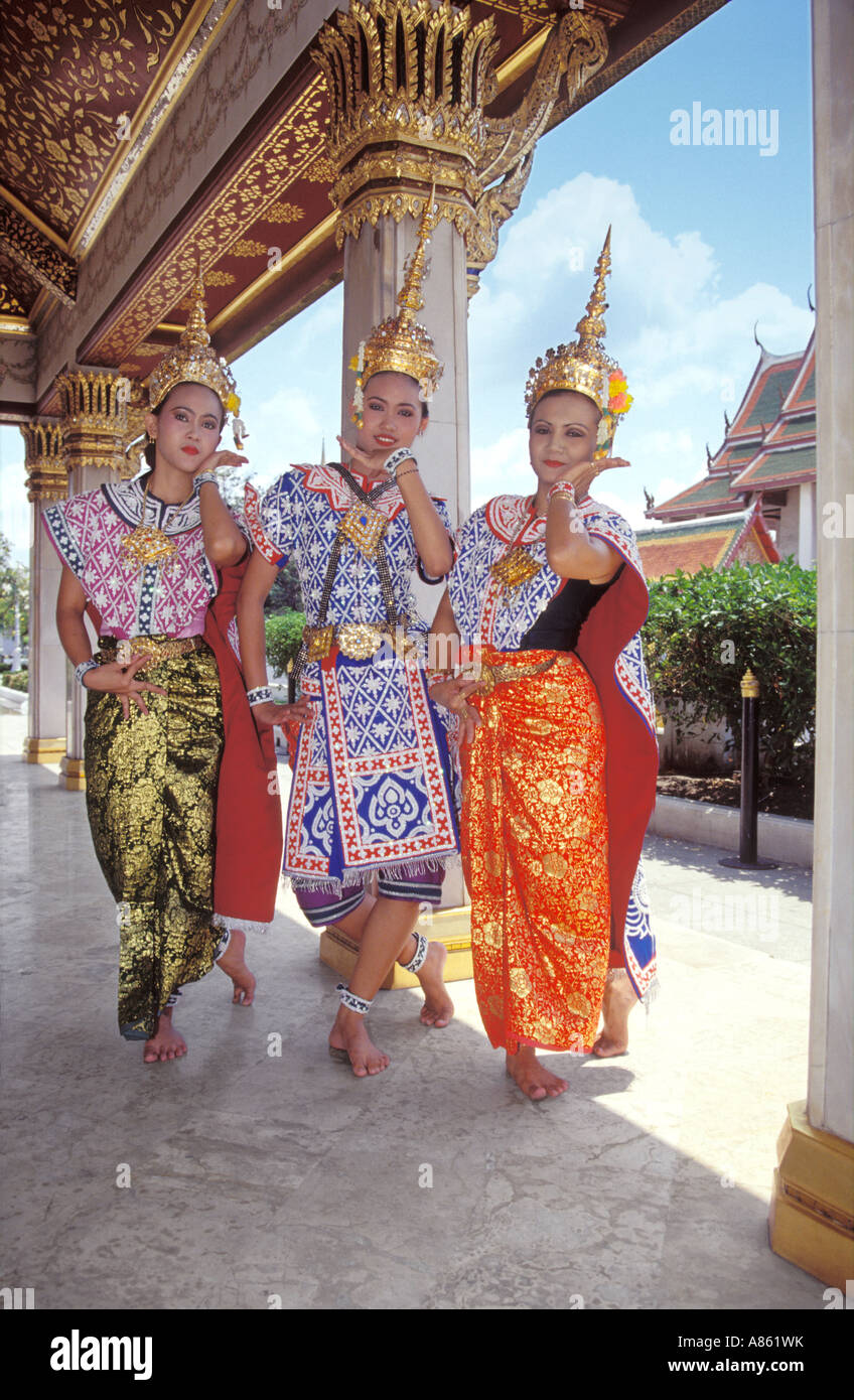 3 Traditional Thai dancers demonstrating dance movements  within gold and red pavilion at temple Wat Ratchanatdaram, Mahachak Road,  Bangkok, Thailand Stock Photo
