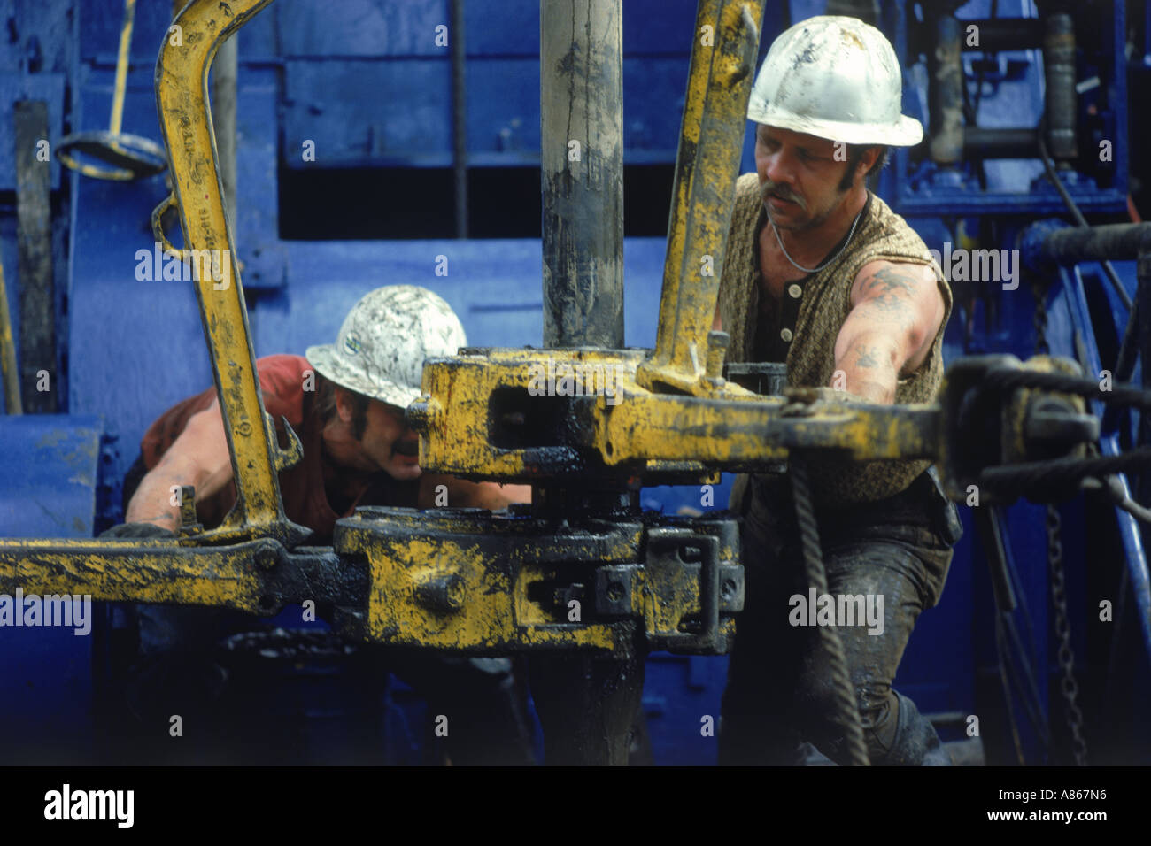 Men working on offshore oil rig coupling drill bits Stock Photo