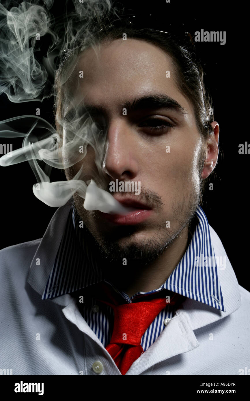 Close-up of young man with smoke coming out of his mouth Stock Photo