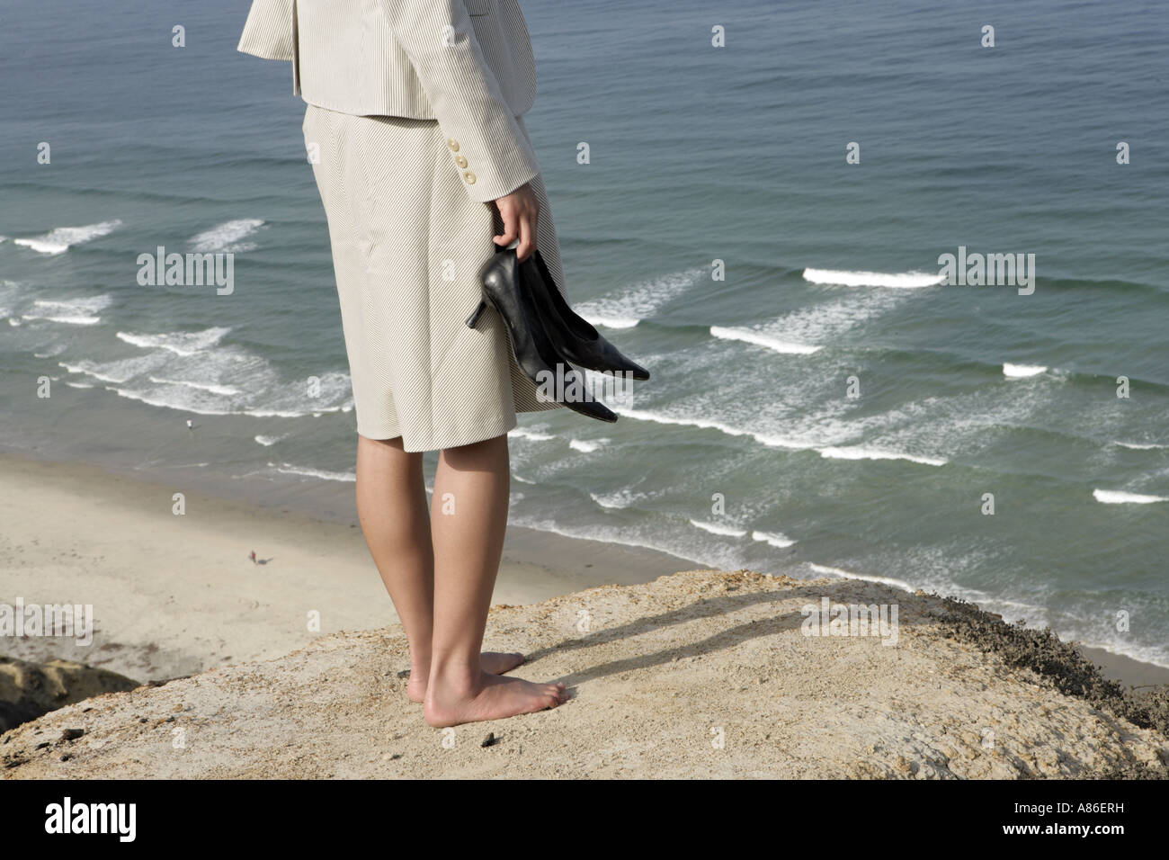 View of a woman standing on a cliff. Stock Photo