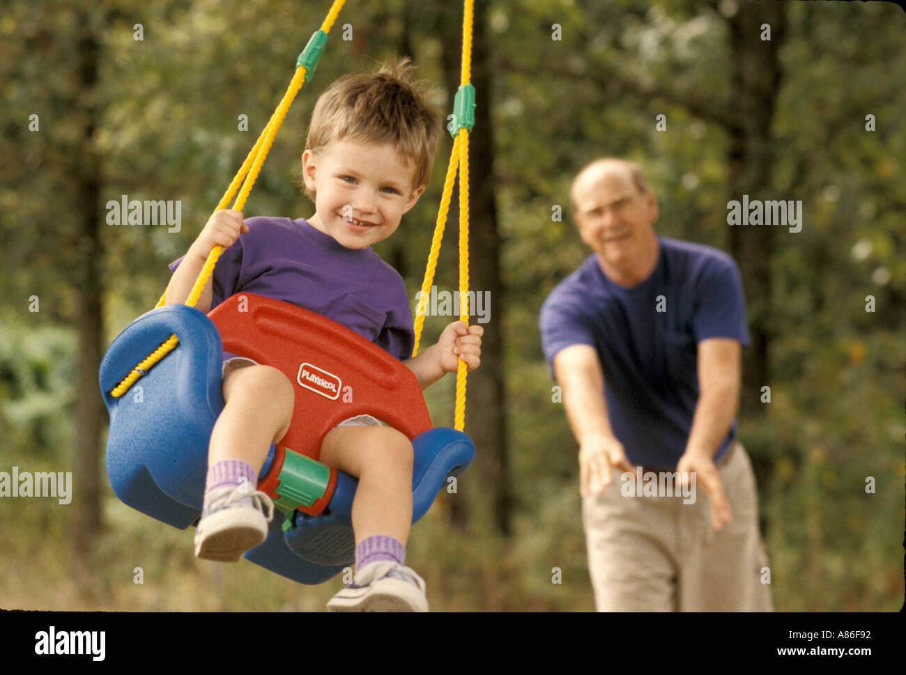 Boy swinging with granddad Stock Photo