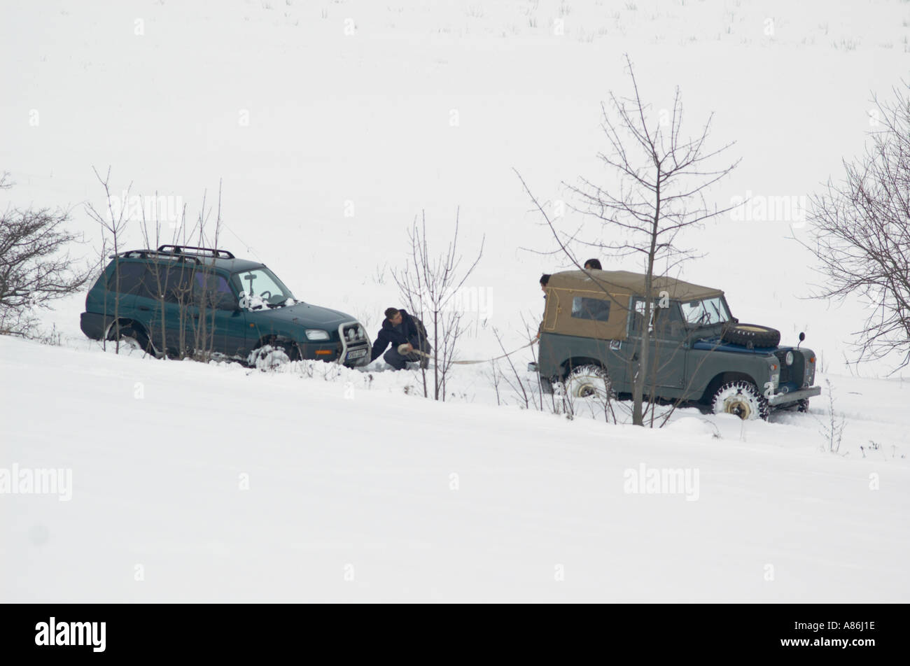 A 1965 Land Rover Series IIa short wheel base softtop recovering a japanese 4WD stuck in snow. Germany, Thuringia 2005. Stock Photo