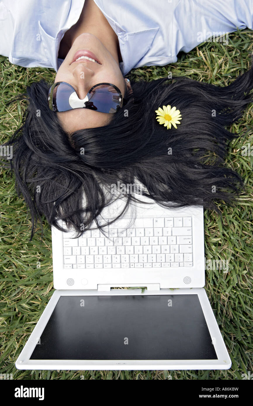 View of a woman sleeping on the grass with a flower in her hair. Stock Photo