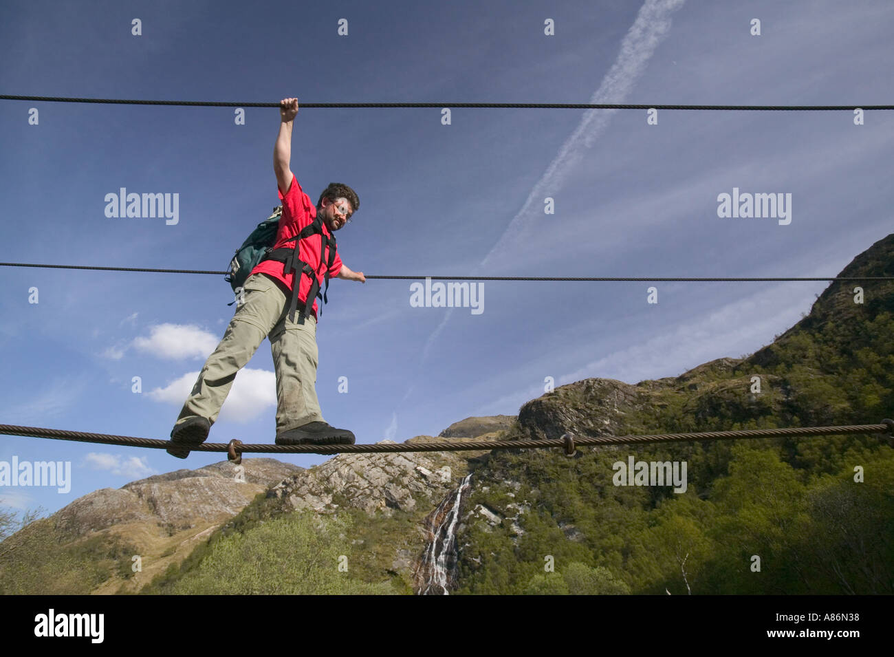 a climber crosses the rope bridge in Glen Nevis at Steall falls Stock