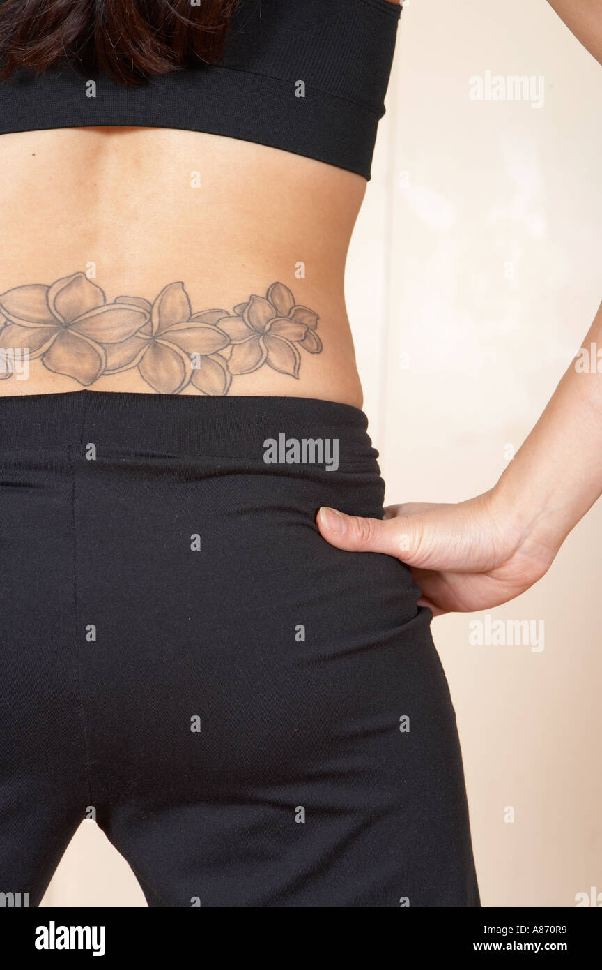 view of a woman's tattooed lower back, with one hand  on her hip Stock Photo