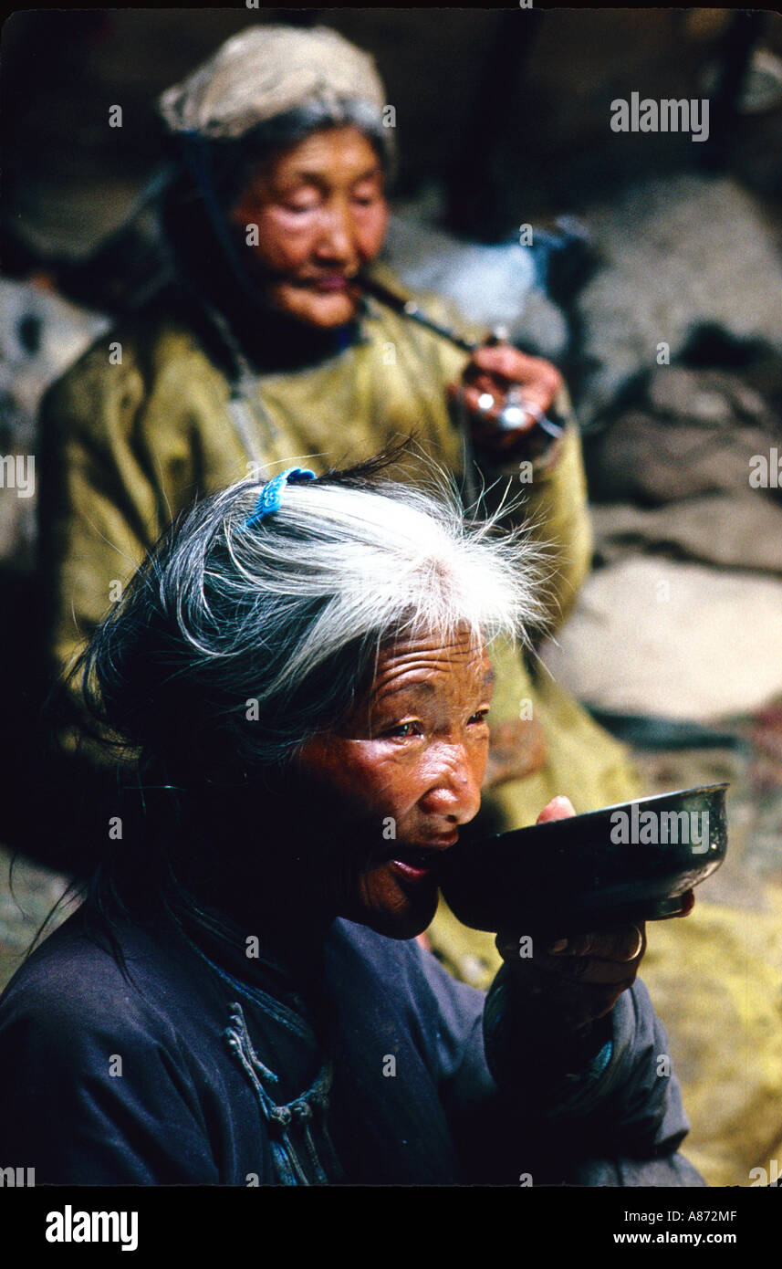 Mongolia a old shaman lighting her pipe while her daughter is