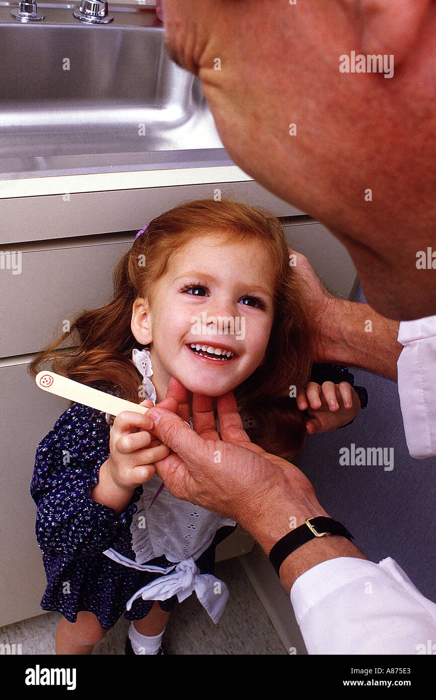 Young redhead girl smiles up at a male doctor dentist as he hands her a new toothbrush Stock Photo